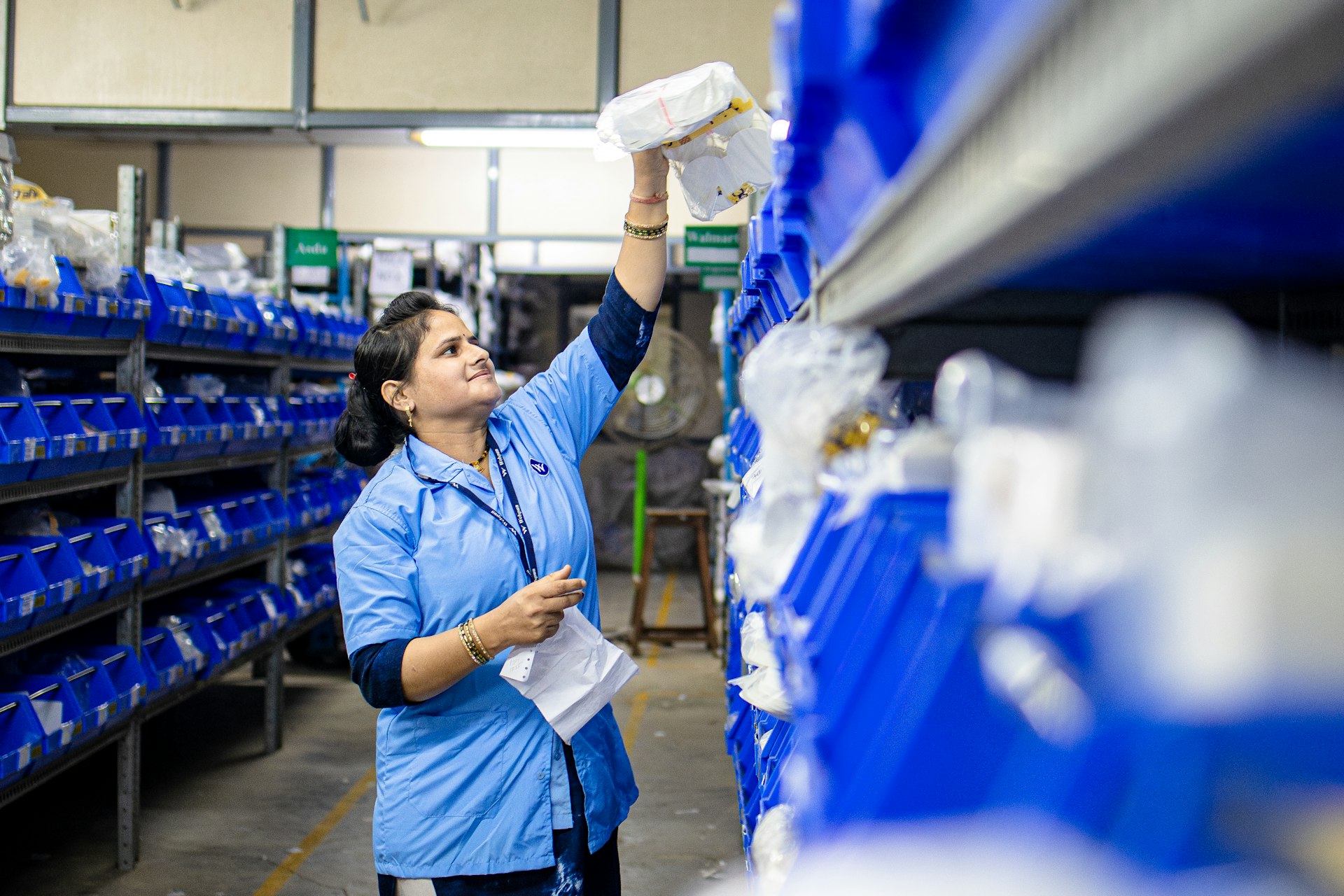 Woman takes item from shelf in a warehouse.